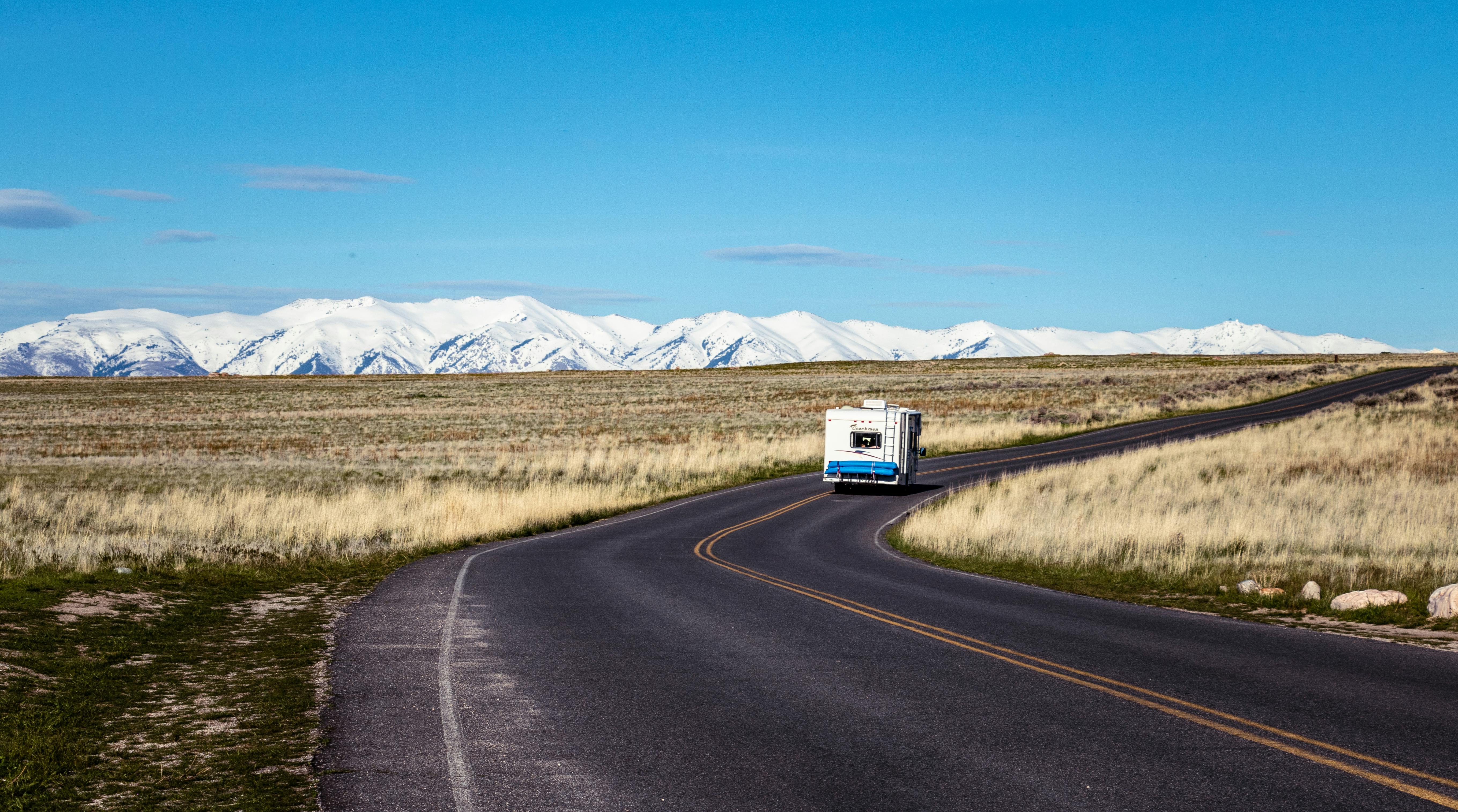 A recreational vehicle on an open road with mountains on the horizon